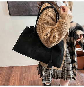 Close-up of black suede tote bag being worn by a model in a cozy autumn setting