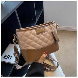 Detail showing the quilted rhombus pattern and contrast wide shoulder strap on the bucket bag