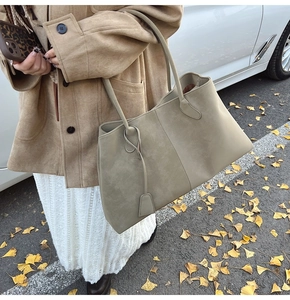 Detail of olive green large suede tote bag featuring a matte texture and minimalist straps