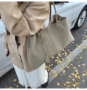 Detail of grey-green faux suede tote bag with stitched seams and slender shoulder strap