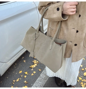Close-up of a large sage green suede tote bag showing texture and side leather charm