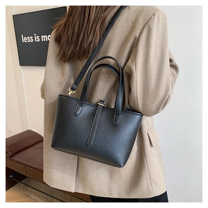 Rear view of a black pebble grain leather tote bag with gold hardware and strap details
