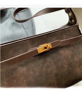 Dettaglio della chiusura a girello dorata su una borsa a tracolla marrone vintage