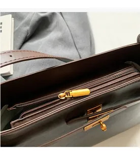 Dettaglio della borsa a tracolla in pelle marrone scuro con chiusura a rotazione dorata e zip