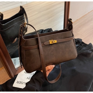 Dettaglio borsa a spalla marrone scuro con chiusura a scatto dorata vista allo specchio