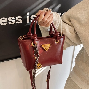 Sac à main trapèze bordeaux vintage avec poignées à nœuds et pendentif clochette