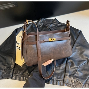 Dettaglio della borsa vintage marrone scuro con chiusura dorata su sfondo di pelle nera