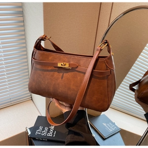 Dettaglio borsa vintage in pelle marrone con chiusura girevole oro e giochi di luce
