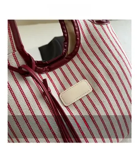 Detail of red and white striped canvas tote bag with burgundy leather trim and stitching