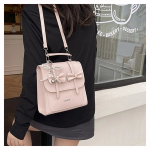 Sac à dos rose avec nœud et pendentif perle dans un style urbain très chic