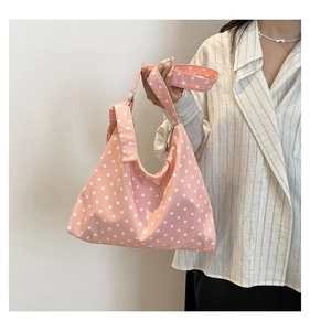 Dettaglio della borsa tote in tela rosa a pois bianchi con ampia tracolla in primo piano