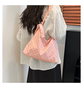 Vista dettagliata della borsa tote in tela a pois rosa con ampia tracolla annodata