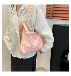 Vista laterale della borsa tote in tela rosa a pois indossata da una modella