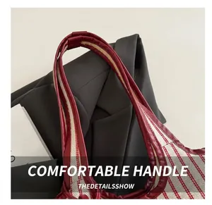 Close-up of red and white striped tote bag showing deep red leather handles and texture