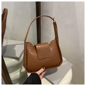 Détail d'un sac sous le bras en cuir tressé marron avec rabat et bandoulière chic
