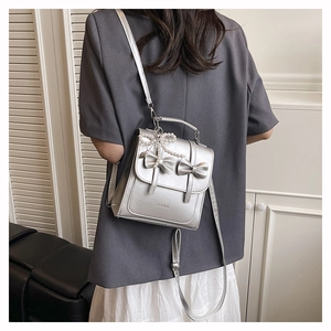 Mini sac à dos argenté avec nœud et perle, porté en bandoulière pour un style chic