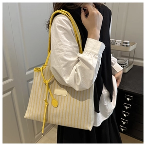 Detail of yellow striped canvas tote bag showing the texture and stylish shoulder strap