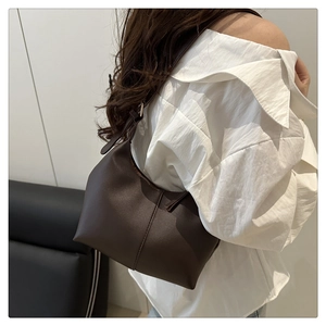 Rear side view of a model wearing a dark brown PU leather shoulder bag with zipper closure
