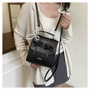 Détail du sac à nœud noir avec pendentif perle et bandoulière en cuir réglable