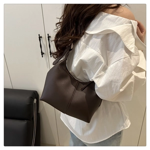 Brown faux leather tote bag worn by a model in a minimalist home setting