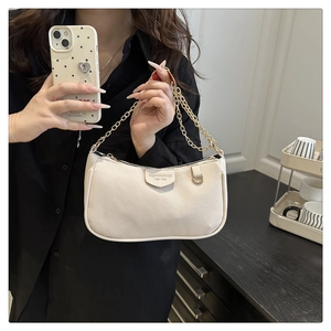 Detail of creamy white litchi grain leather bag with gold chain and fashion logo