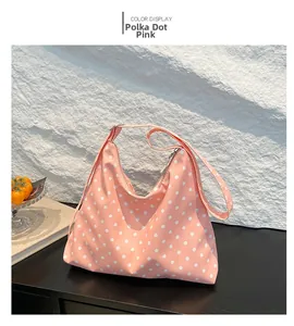 Dettaglio ravvicinato della borsa hobo rosa a pois con ampia tracolla in tela