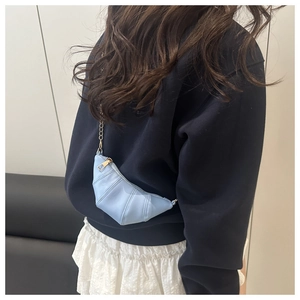 Détail du mini sac croissant bleu clair avec texture matelassée et chaîne dorée