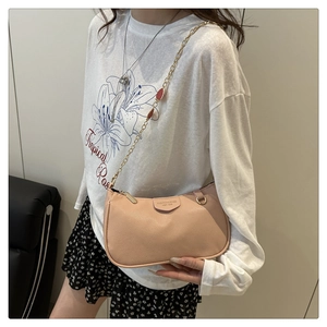 Detail der nude-rosa Crossbody-Tasche mit Lychee-Muster, Goldkette und rotem Anhänger