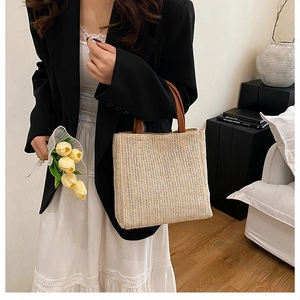 Détail du sac cabas en paille avec poignées en cuir marron et motif de tissage chevrons
