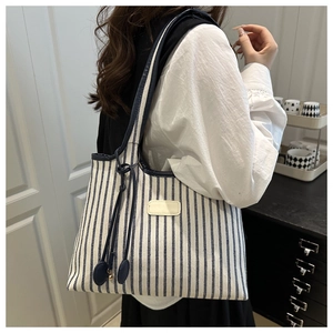 Detail of blue and white striped tote bag with navy leather trim and blank logo patch