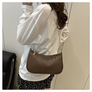 Detailed close-up of brown litchi pattern leather shoulder bag with gold chain and strap