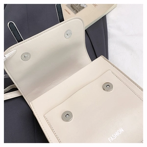 Détail du sac en cuir crème montrant le fermoir magnétique et le logo Fashion brodé