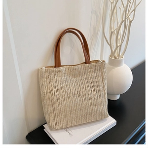 Détail du sac cabas en paille tissée avec anses en cuir marron et texture ondulée
