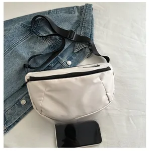Gros plan du sac croissant en nylon beige avec fermeture éclair noire et mobile