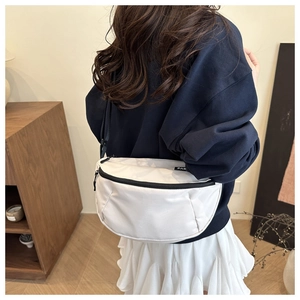 Close-up of white crescent crossbody bag on model, showing size and nylon material
