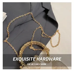Detail of elegant gold metal chain and pearl-encrusted ring handle on the floral handbag