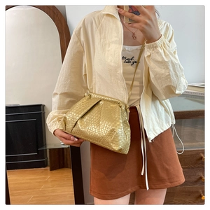 Metallic gold woven cloud bag with soft pleats and thin strap shown on a model