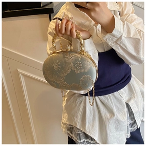 Detail of grey-green satin evening clutch with gold floral embroidery and carved metal handle