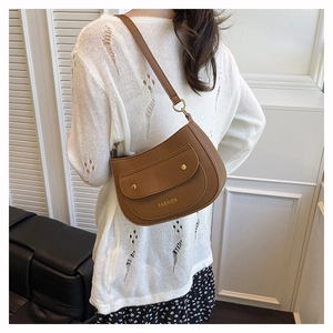 Detail of caramel crescent crossbody bag with lychee texture and gold fashion lettering
