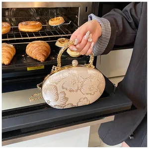 Detailed view of cream silk evening bag featuring floral embroidery and gold handle