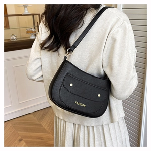 Close-up of black lychee grain leather shoulder bag with golden FASHION logo detail
