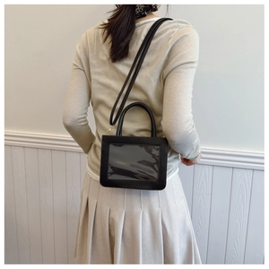 Détail d'un sac bandoulière en cuir noir avec fenêtre transparente porté par un mannequin