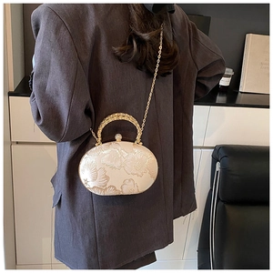 Detail of embroidered floral texture on round evening bag with gold chain strap