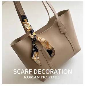Detail of beige leather tote bag with elegant geometric silk scarf wrapped on handle