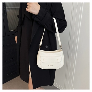 Detail of cream crossbody bag featuring lychee texture leather and gold studs