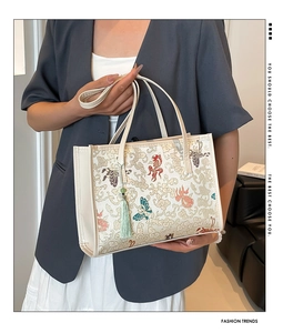 Detail of embroidered tote bag with traditional fish and butterfly patterns and tassel