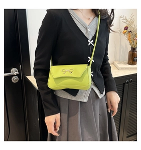 Dettaglio borsa a tracolla verde lime con un sottile fiocco dorato sulla patta