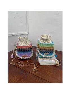 Close-up of knit bucket bags with pearl handles and drawstring closures on a table