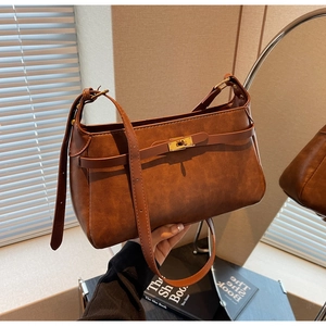 Dettaglio di borsa vintage in pelle marrone con chiusura a scatto dorata e tracolla