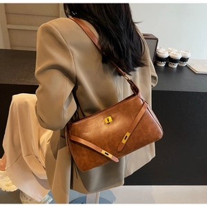 Borsa a spalla vintage in ecopelle marrone con chiusura dorata indossata da modella